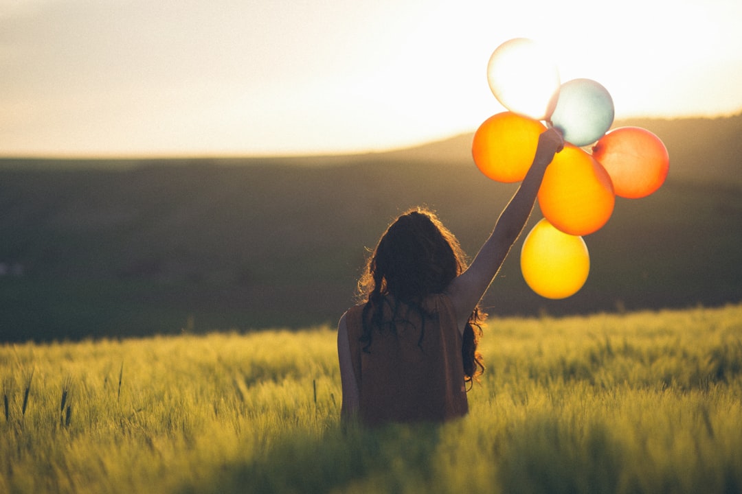 Photo by Catalin Pop unknown person holding balloons outdoors
